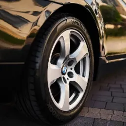 Błyszczący czarny samochód z aluminiowymi felgami i oponami Hankook Ventus, zaparkowany na brukowanej nawierzchni.