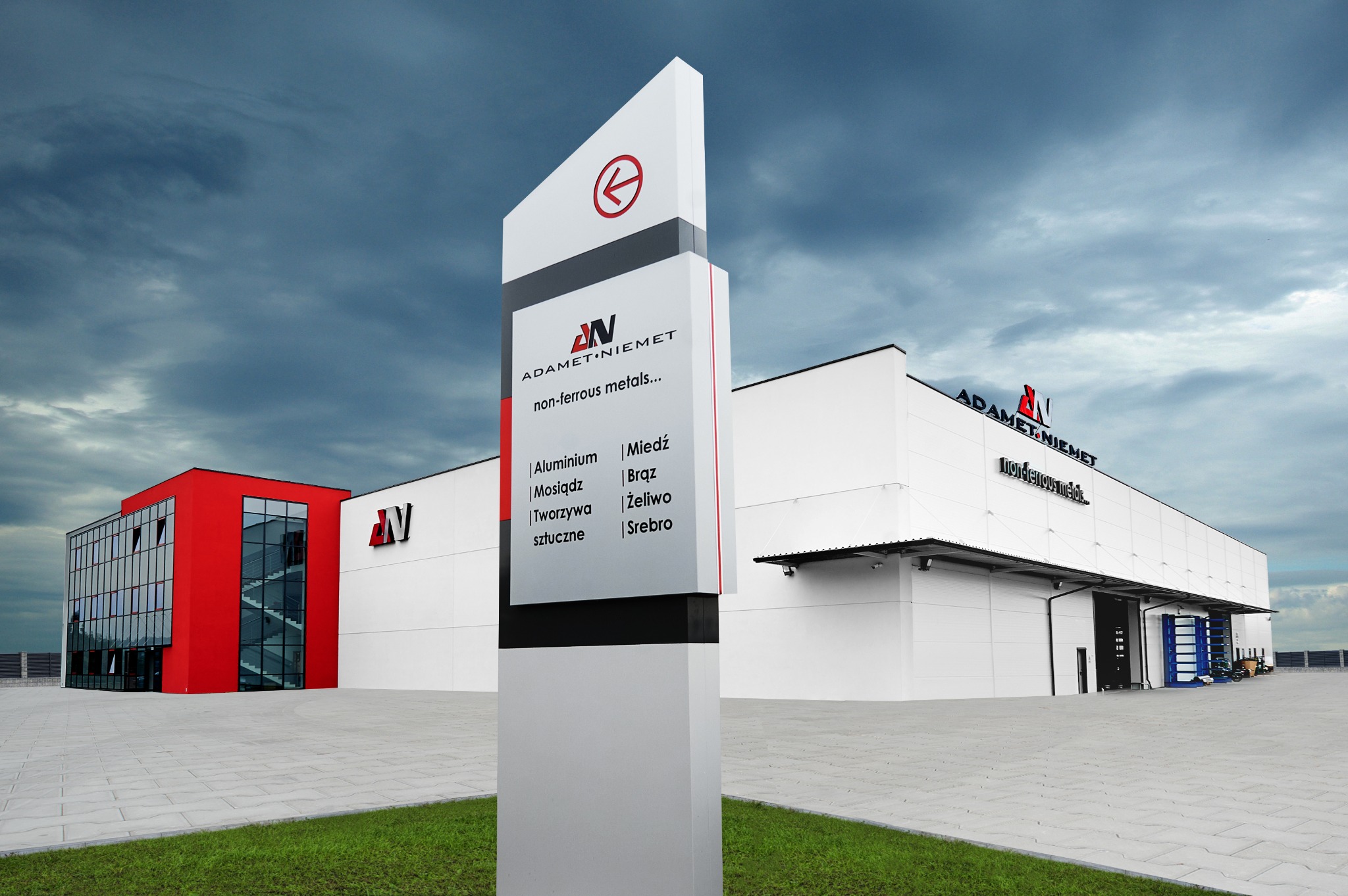 Zewnętrzny widok budynku firmy Adamet Niemet z tablicą informacyjną prezentującą logo i ofertę metali nieżelaznych: aluminium, miedź, mosiądz, brąz, żeliwo, tworzywa sztuczne i srebro.