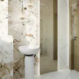 Nowoczesna łazienka z umywalką na postumencie, marmurowymi ścianami i podłogą, złotą armaturą oraz wiszącymi lampami z abażurami, odbicie lustrzane w szklanej ściance prysznica.