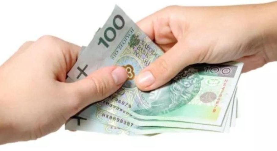 Dłonie liczą plik banknotów 100 zł na białym tle.