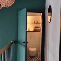 Katarzyna Kuczyńska Projektowanie Wnętrz - Otwarta, turkusowa łazienka z wzorzystą podłogą, widziana z korytarza z drewnianą podłogą ułożoną w jodełkę, ciemnozielone ściany i ozdobne lampy.