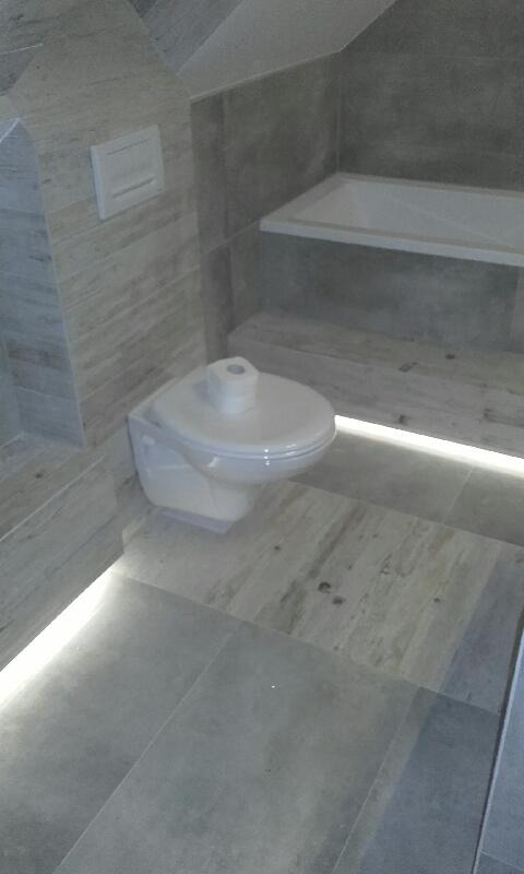 Nowoczesna łazienka na poddaszu z podświetleniem LED pod toaletą i półką obudowaną płytkami imitującymi drewno