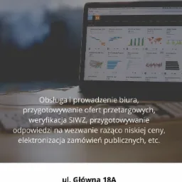 Laptop wyświetlający dashboard z danymi analitycznymi, umieszczony na biurku, z widocznym tekstem o obsłudze biura i zamówieniach publicznych.