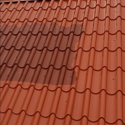 Pokrycia Dachowe Paweł Poniatowski - Czerwona dachówka modułowa po czyszczeniu fragmentu, widoczna różnica w kolorze. Niebo z chmurami w tle.