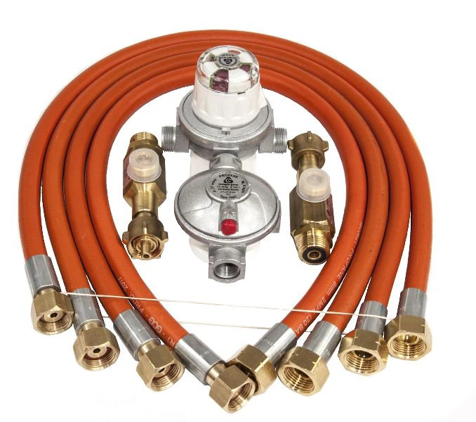 Zestaw przyłączeniowy do butli gazowej: reduktory ciśnienia, węże w oplocie i złączki na białym tle.