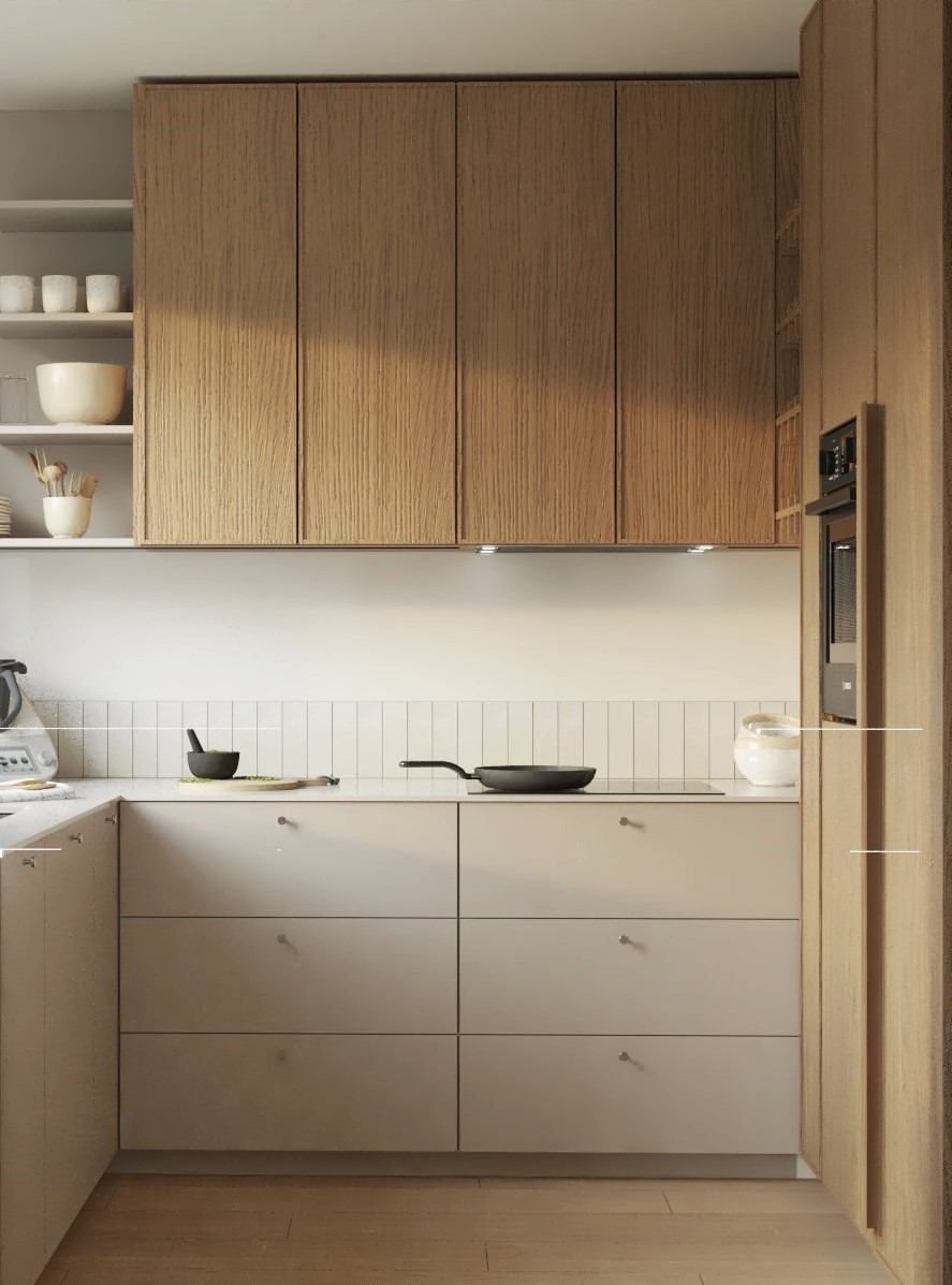 Jasna, minimalistyczna kuchnia z drewnianymi szafkami górnymi i szarymi dolnymi. Na blacie widoczna patelnia, moździerz z pistacjami i biała ceramika. Nad blatem białe, prostokątne płytki.