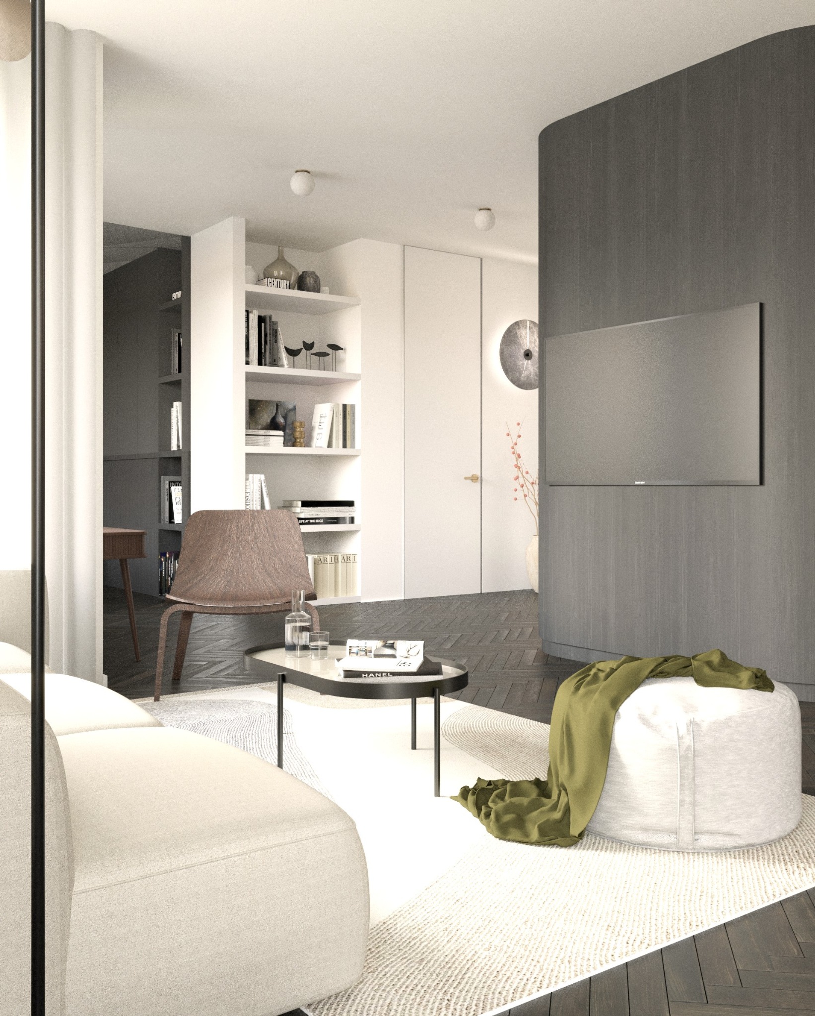 Jasne, przestronne wnętrze salonu z kremową sofą, okrągłym pufem z zielonym pledem, stolikiem kawowym z książkami i krzesłem na tle regału z książkami.