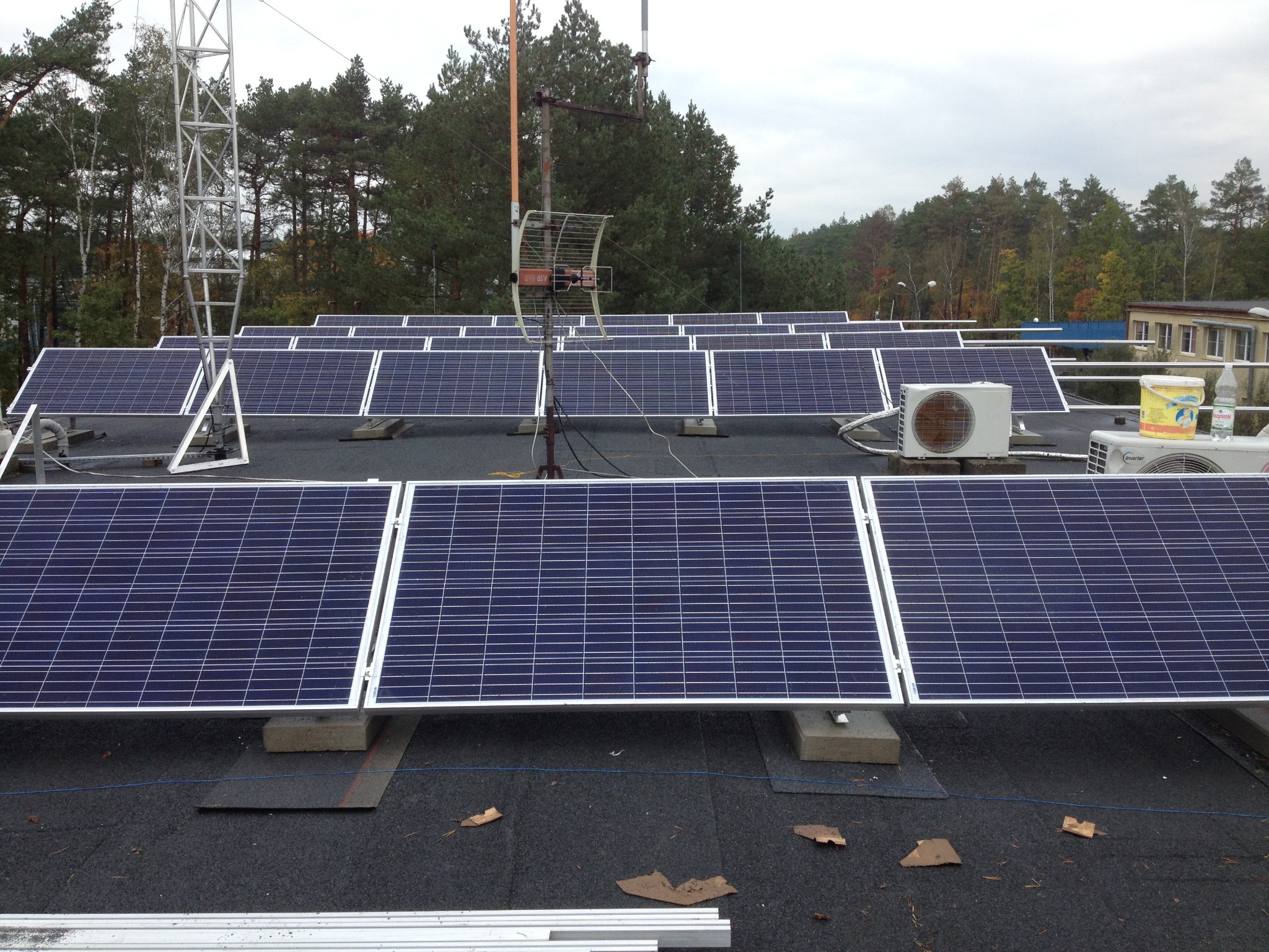 Instalacja paneli słonecznych na dachu budynku w Częstochowie, widoczne również jednostki klimatyzacyjne i antena telewizyjna.