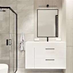 Nowoczesna łazienka w jasnych barwach z kabiną prysznicową z czarnymi ramami, białą umywalką z dwoma szufladami, lustrem z podświetleniem LED i wiszącą toaletą.