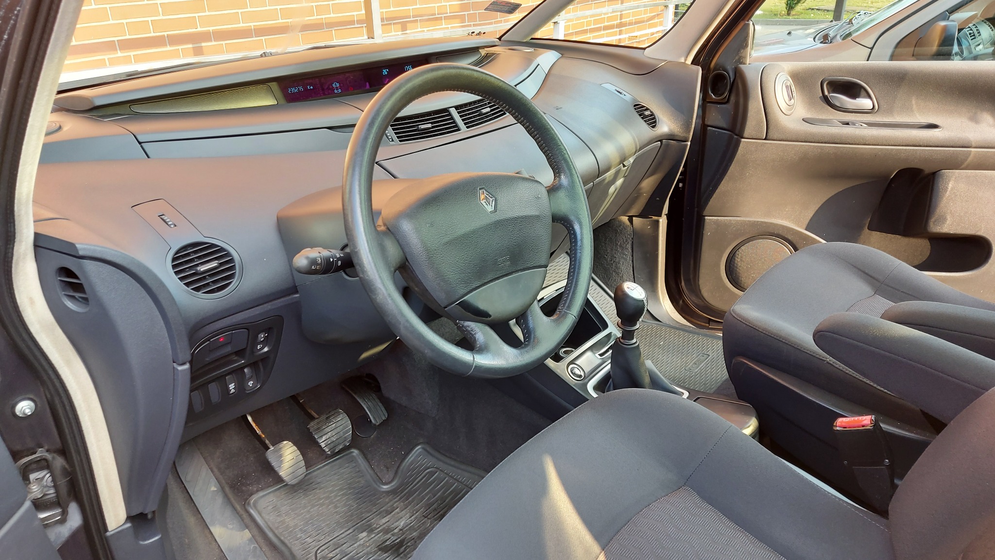 Wnętrze samochodu Renault Espace, widok na deskę rozdzielczą, kierownicę z logo, fotel kierowcy i dźwignię zmiany biegów. Widoczny przebieg na wyświetlaczu.