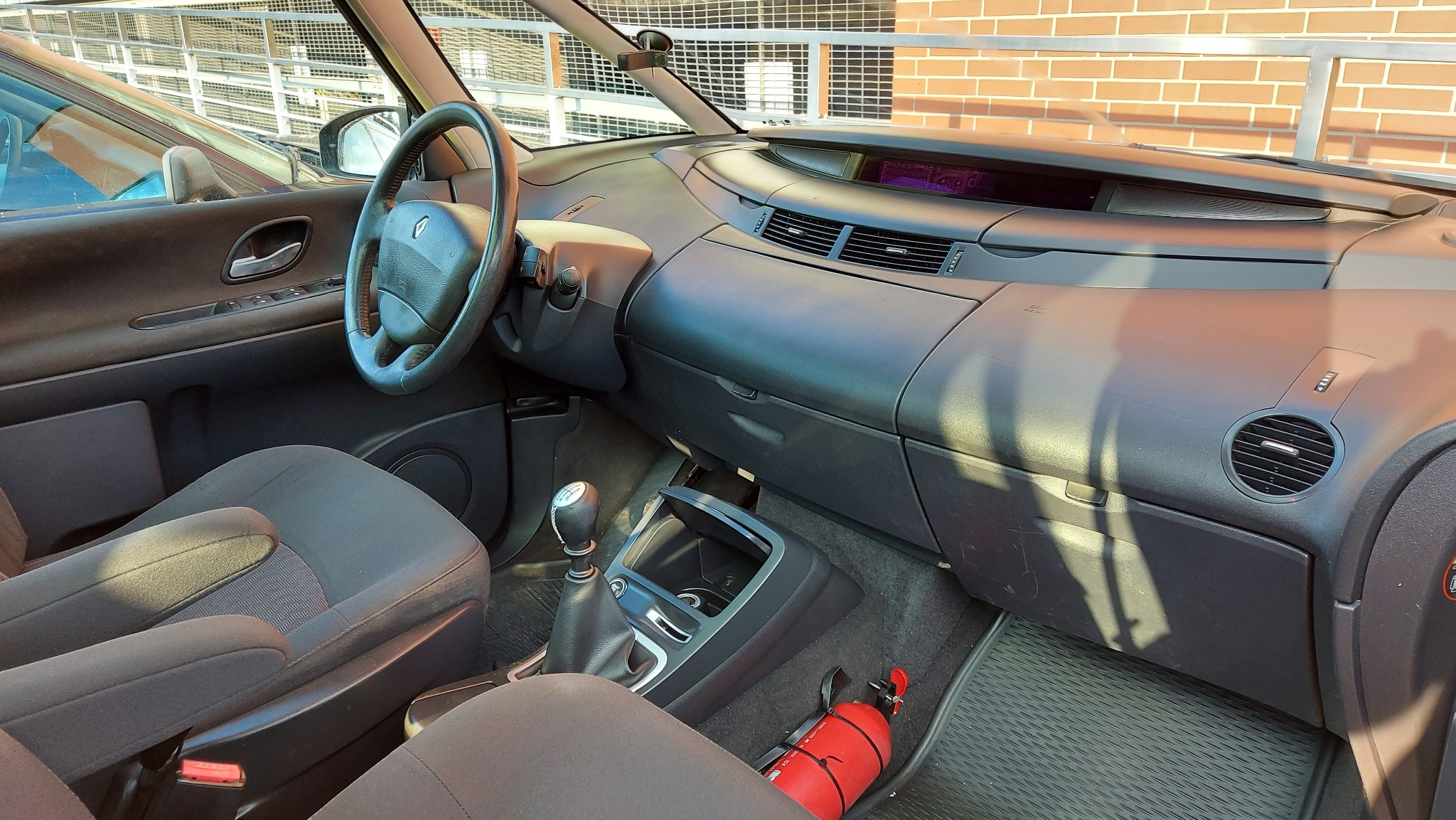 Wnętrze samochodu Renault Espace z widoczną gaśnicą na podłodze pasażera.