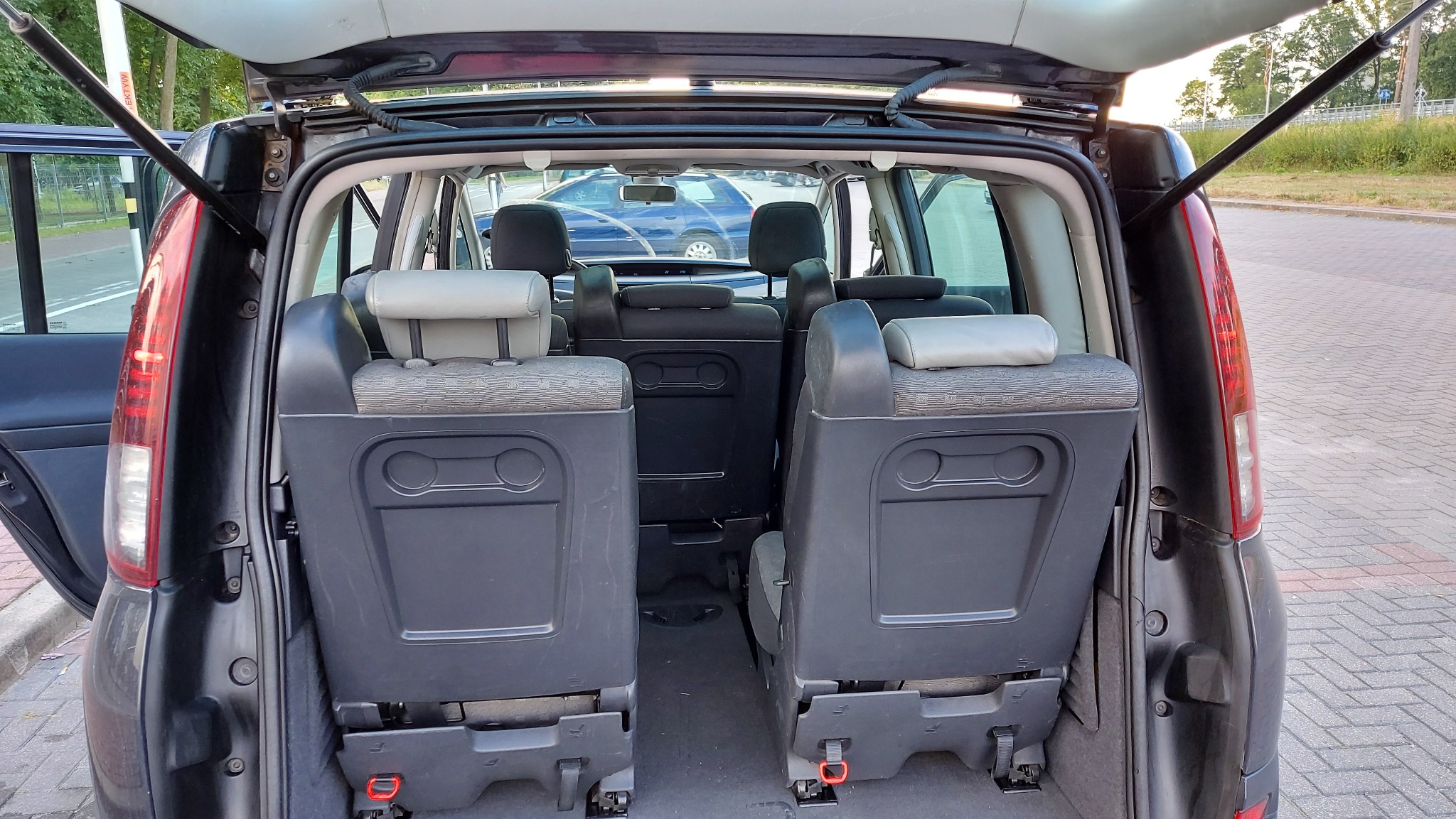 Wnętrze bagażnika samochodu osobowego z rozłożonymi siedzeniami, widoczne uchwyty mocujące i szara tapicerka.