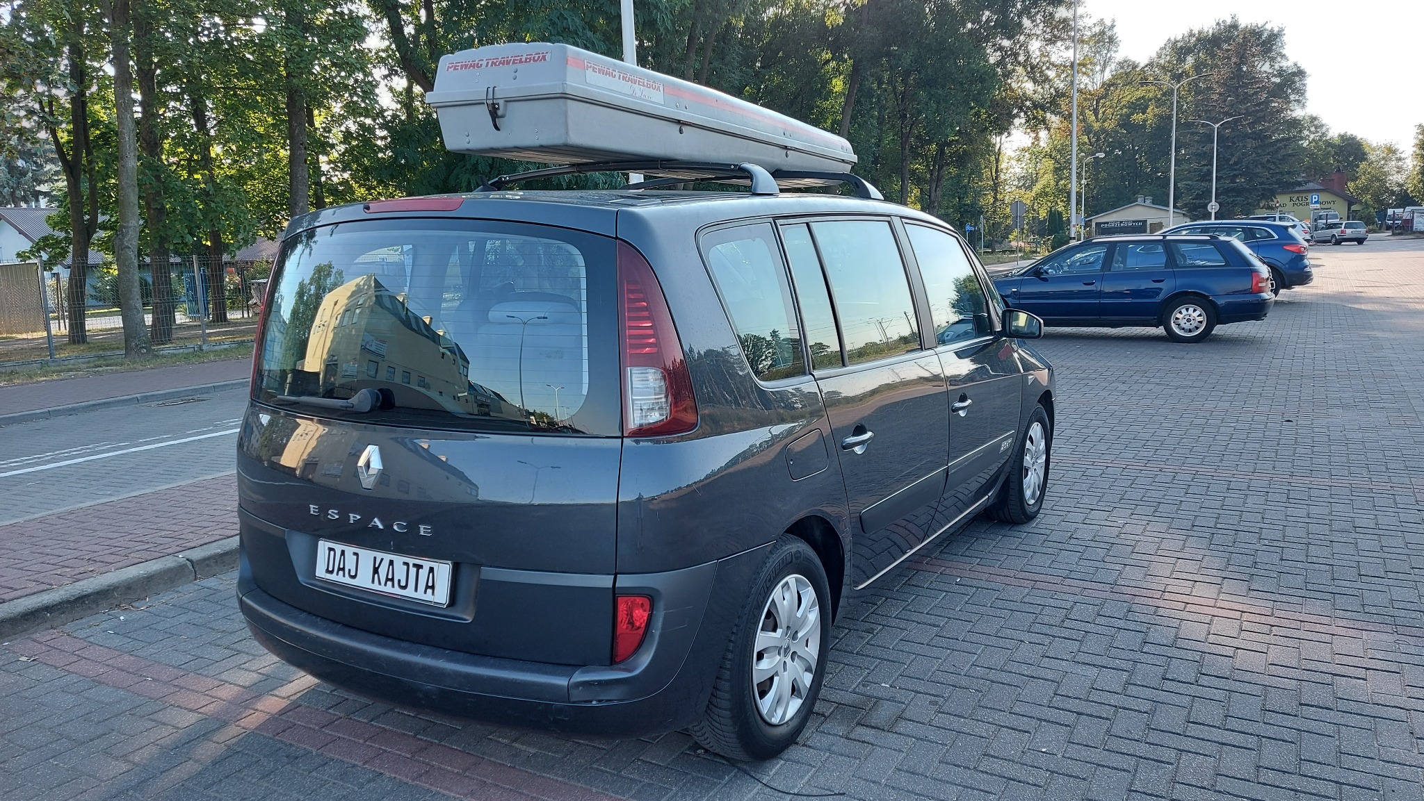 Szary samochód Renault Espace z bagażnikiem dachowym Pewag Travelbox zaparkowany w Świdniku na brukowanym parkingu, widok z tyłu.