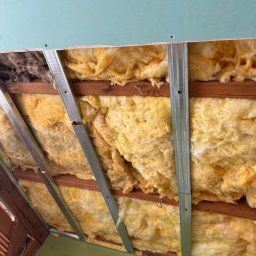 Usługi budowlane DARO - Ocieplenie poddasza wełną mineralną, widoczne metalowe profile, drewniana konstrukcja i fragment płyty gipsowej.