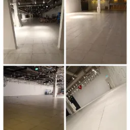 Rozległa przestrzeń handlowa z jasnymi, kwadratowymi płytkami podłogowymi, widoczne instalacje oświetleniowe sufitowe, przygotowywana do otwarcia sklepu, z napisami 'FUN' i 'SINSA' na ścianach.