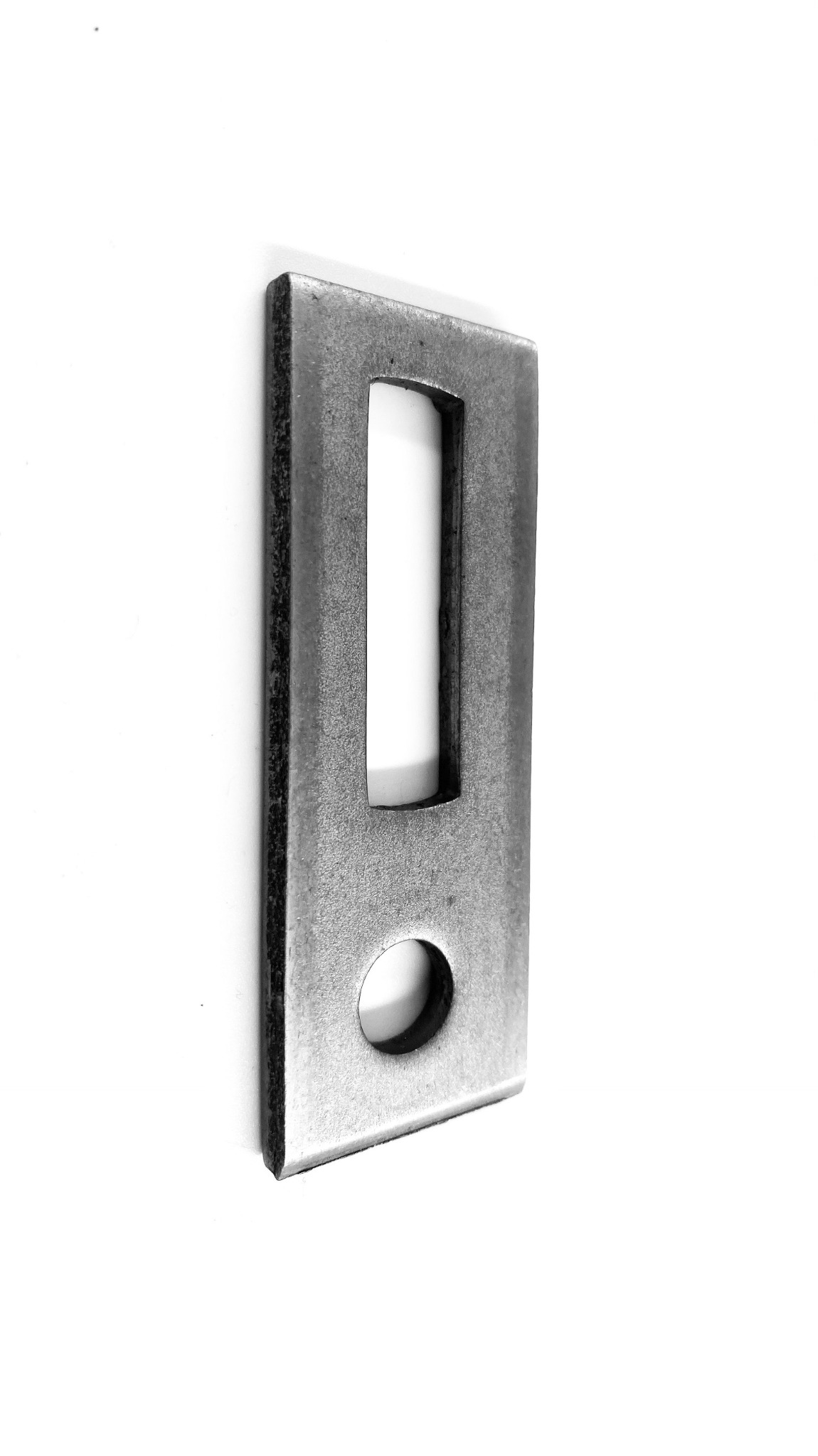 Metalowy uchwyt montażowy z otworem na śrubę i prostokątnym wycięciem, widoczna faktura stali.