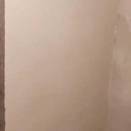 Świeżo nałożona, jasna warstwa gładzi szpachlowej na ścianie w rogu pomieszczenia, z widocznymi śladami po szpachelce, tworzącymi delikatną fakturę.