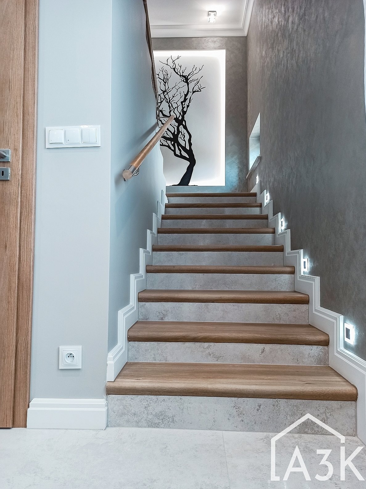 Schody w okładzie z wielkoformatowych gresów w połączeniu z tynkiem dekoracyjnym oraz cokołami ze sztukaterii.