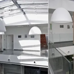 Wnętrze nowoczesnego Centrum Diagnostyki Obrazowej w Krakowie z przeszklonym dachem, wiszącymi lampami w kształcie kopuł i przeszklonymi balustradami na antresoli.