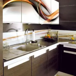 Nowoczesna kuchnia z ciemnymi drewnianymi szafkami i białymi uchwytami, górne szafki z grafiką abstrakcyjną w odcieniach bieli, pomarańczy i szarości, chromowany zlew i bateria.