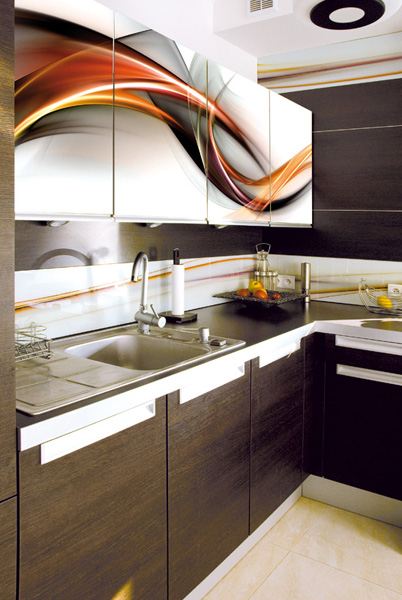Nowoczesna kuchnia z ciemnymi drewnianymi szafkami i białymi uchwytami, górne szafki z grafiką abstrakcyjną w odcieniach bieli, pomarańczy i szarości, chromowany zlew i bateria.