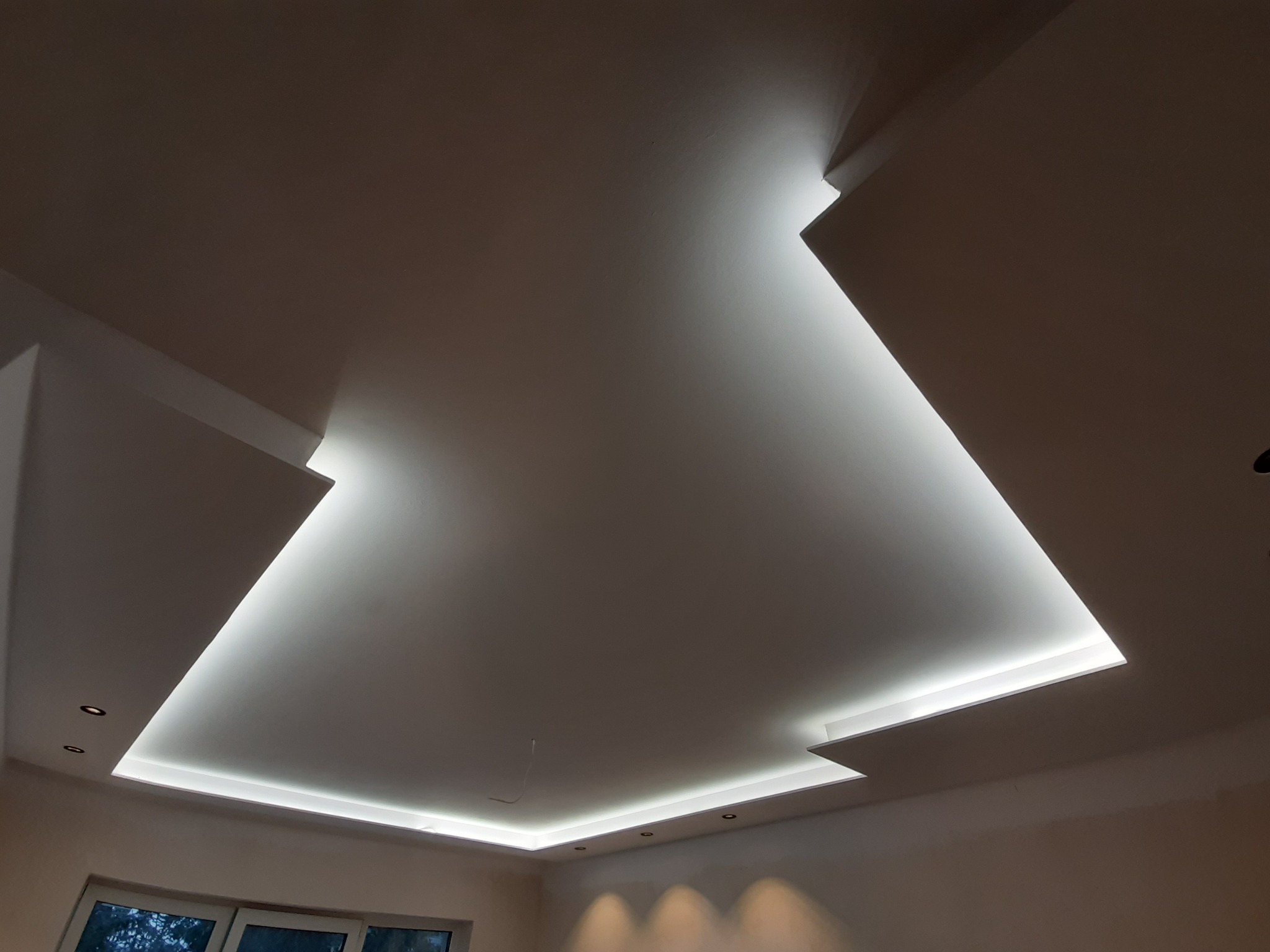 Nowoczesny sufit podwieszany z oświetleniem LED, widoczne wnęki i punktowe lampy halogenowe, świeżo po remoncie.