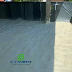 Poddasze po ociepleniu pianką PUR, widoczne czarne folie ochronne na ścianach i logo firmy PUR Concept w rogu kadru.