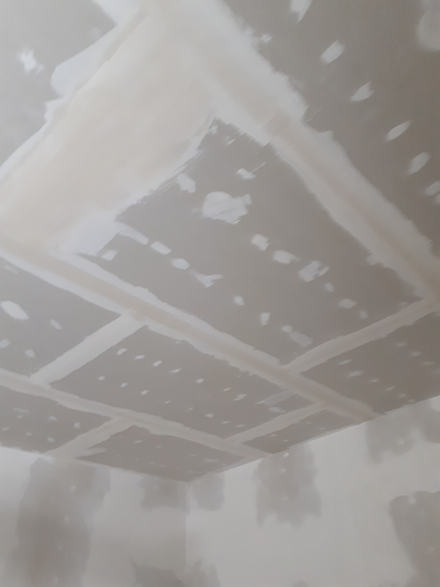 Sufit z płyt kartonowo-gipsowych, częściowo zaszpachlowane łączenia, widoczne niedoskonałości na powierzchni płyt i ścian.