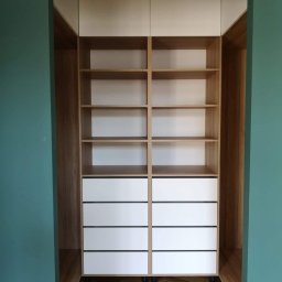 Zakład Stolarski ASKO Joanna Kołodziejska - Wnękowa zabudowa z drewnianymi półkami i białymi szufladami, dopasowana do koloru ścian, na podłodze parkiet ułożony w jodełkę.