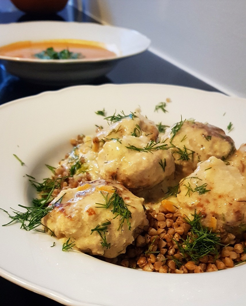 Kluski w kremowym sosie, posypane koperkiem, podane na kaszy gryczanej, zupa krem w tle.