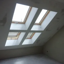 Cztery okna dachowe w skośnym suficie, po szpachlowaniu, przed malowaniem, widoczne ślady po szpachli.