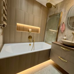 Refit Solutions Paweł Suchocki - Nowoczesna łazienka w beżach z złotymi akcentami: bateria, deszczownica, rama kabiny. Podświetlana wanna i szafka pod umywalką. Minimalistyczny design.