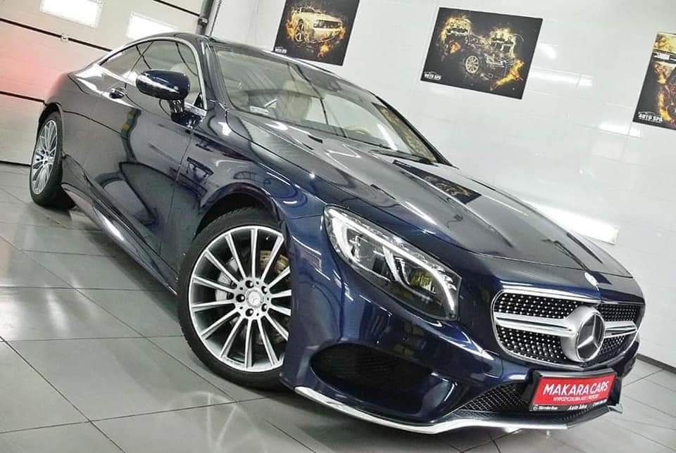 Błyszczący, granatowy Mercedes-Benz S-Class Coupe z aluminiowymi felgami wieloramiennymi, sfotografowany w studiu detailingowym z plakatami samochodów na ścianie, prezentujący usługi pielęgnacji aut.