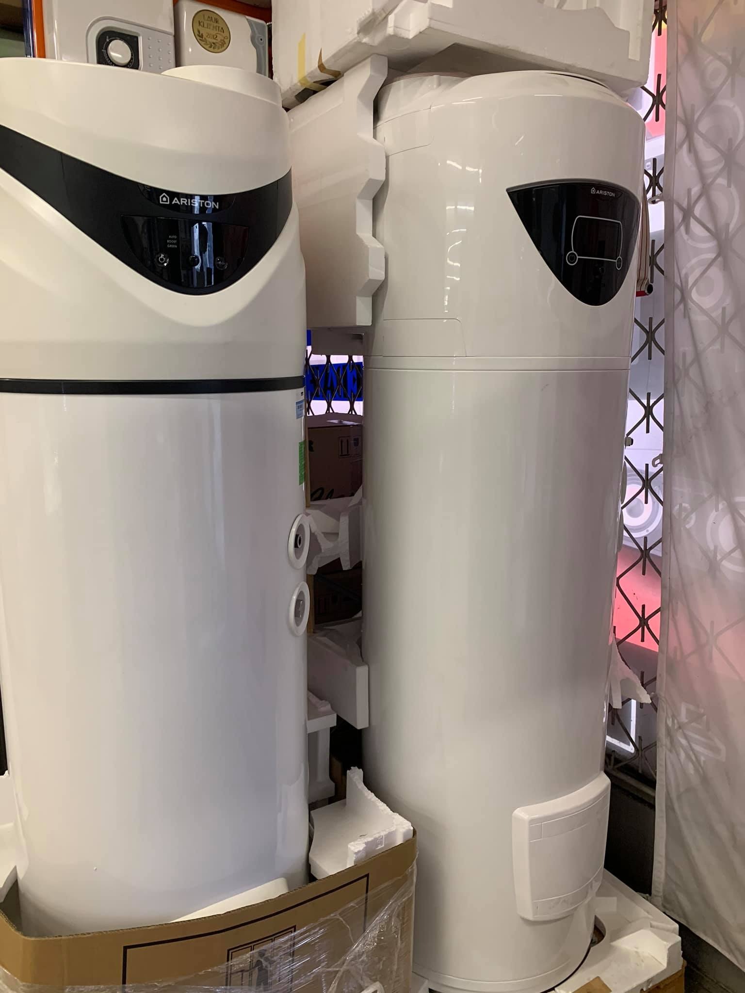 Dwa białe, fabrycznie zapakowane, pionowe podgrzewacze wody marki Ariston, widoczne elementy sterowania i obudowy, zabezpieczone styropianem i folią.