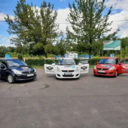 Trzy samochody z otwartymi drzwiami, z logo firmy na karoserii i dachu, stojące na placu manewrowym pod drzewami.