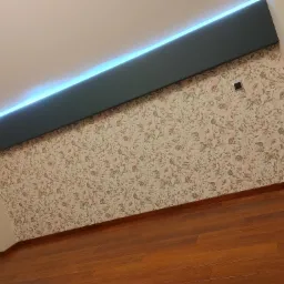 Wnętrze pokoju w Krakowie po remoncie: drewniana podłoga, ściana w kwiaty i podwieszany sufit z oświetleniem LED.