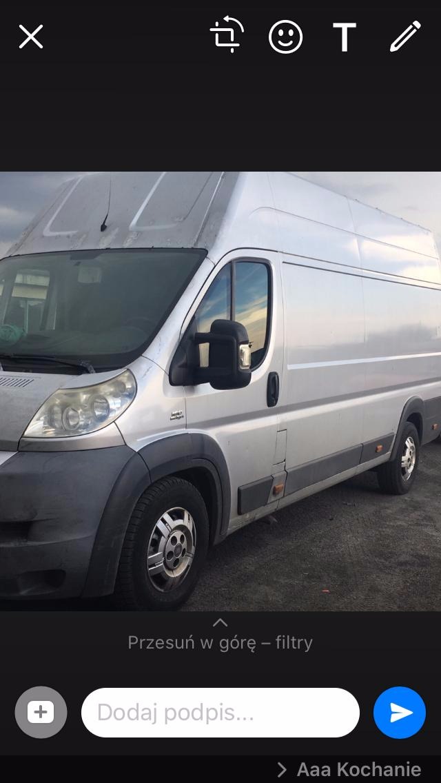 Srebrny bus dostawczy marki Fiat Ducato, widok z boku, lekko zabrudzony, stojący na zewnątrz przy pochmurnym niebie.