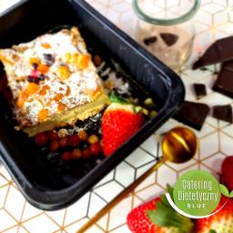 Catering Dietetyczny Blue - Deser z owocami w czarnym pojemniku, obok truskawki, czekolada i koktajl, na geometrycznym tle.