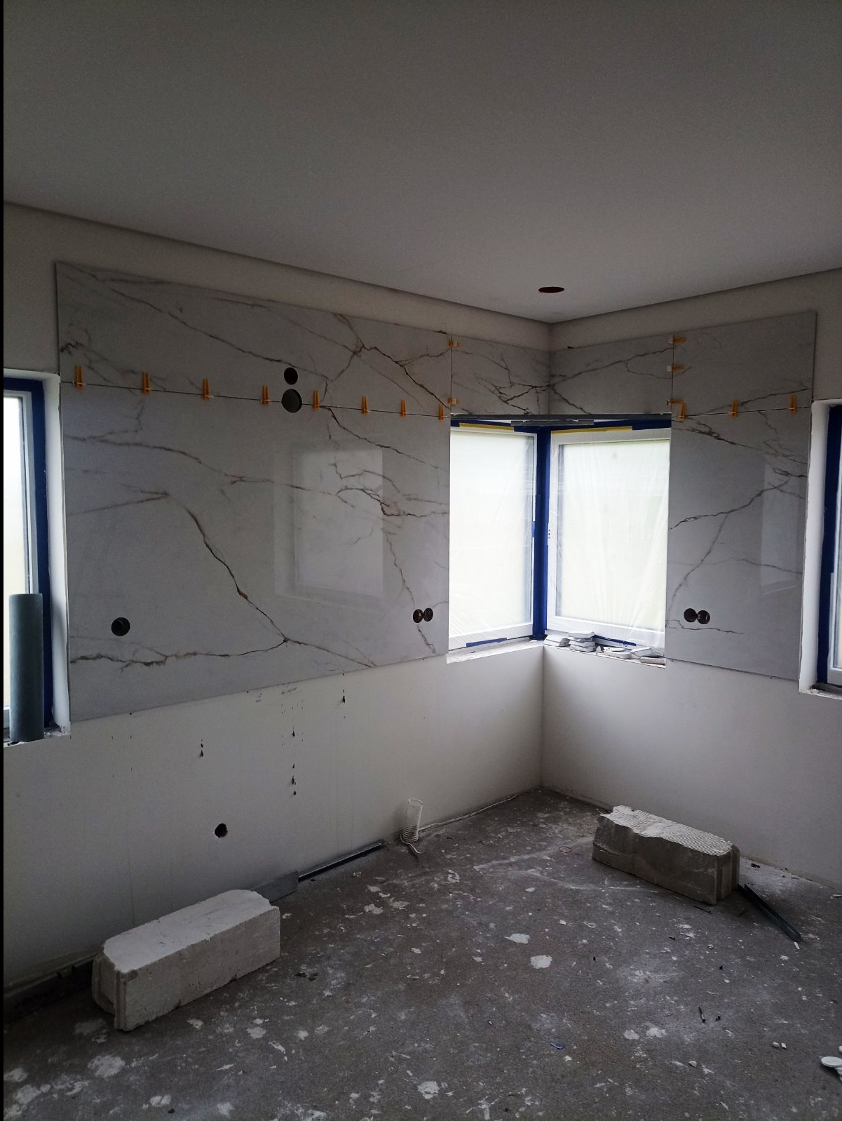 Montaż wielkoformatowych płytek imitujących marmur w kuchni w Słubicach, widoczne plastikowe krzyżyki dystansowe i otwory na gniazdka.