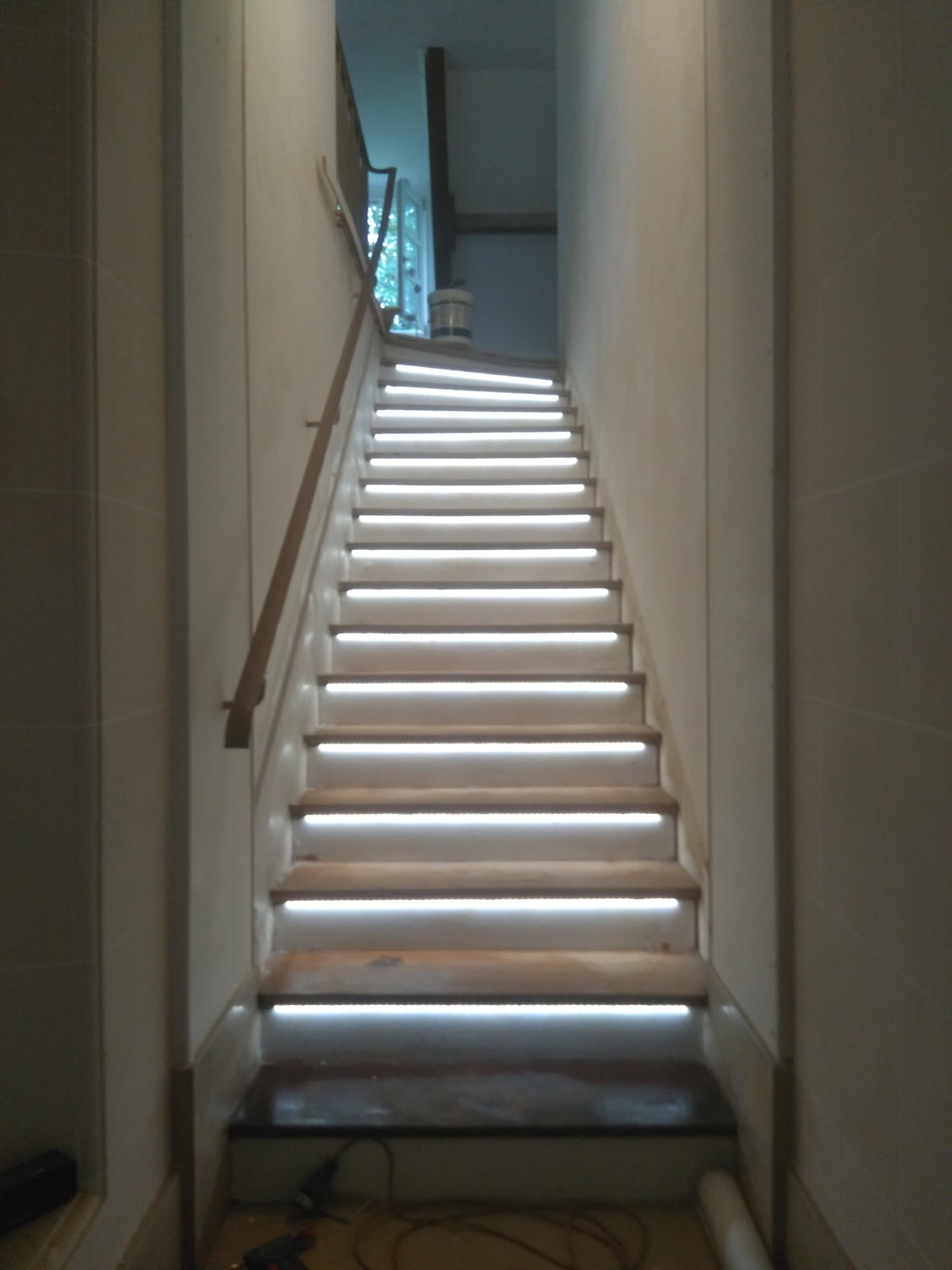 Schody z podświetleniem LED, widok z dołu. Nowoczesne rozwiązanie oświetleniowe w korytarzu. Jasne, równomierne światło podkreśla stopnie.