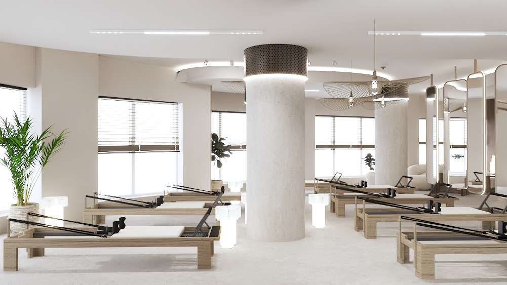 Jasne, przestronne studio pilates z drewnianymi reformerami, kolumnami o surowym wykończeniu i dekoracyjnymi lampami. Rośliny doniczkowe dodają naturalnego akcentu.