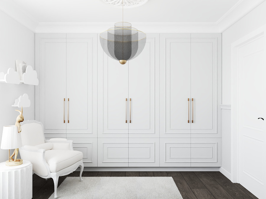 Elegancka, biała szafa wnękowa z frezowanymi frontami i złotymi uchwytami, uzupełniona o fotel w stylu Ludwika i lampę. Całość w jasnym, minimalistycznym wnętrzu.