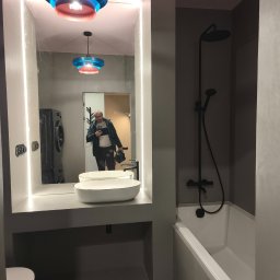 ROYAL BUD Kompleksowe Wykończenia wnętrz YURII TYMOSHCHUK - Nowoczesna łazienka w szarościach z podświetlanym lustrem i designerską lampą. W odbiciu widać osobę robiącą zdjęcie i pralkę. Minimalistyczny styl.