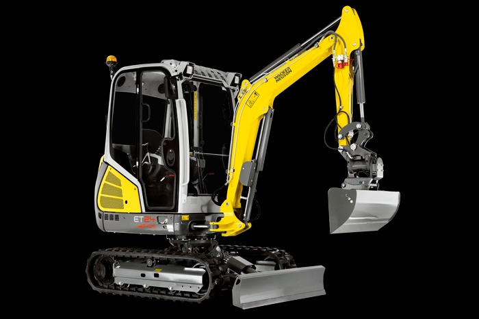 Żółto-szara minikoparka Wacker Neuson ET24 na czarnym tle, widok z przodu, z łyżką skierowaną w dół.