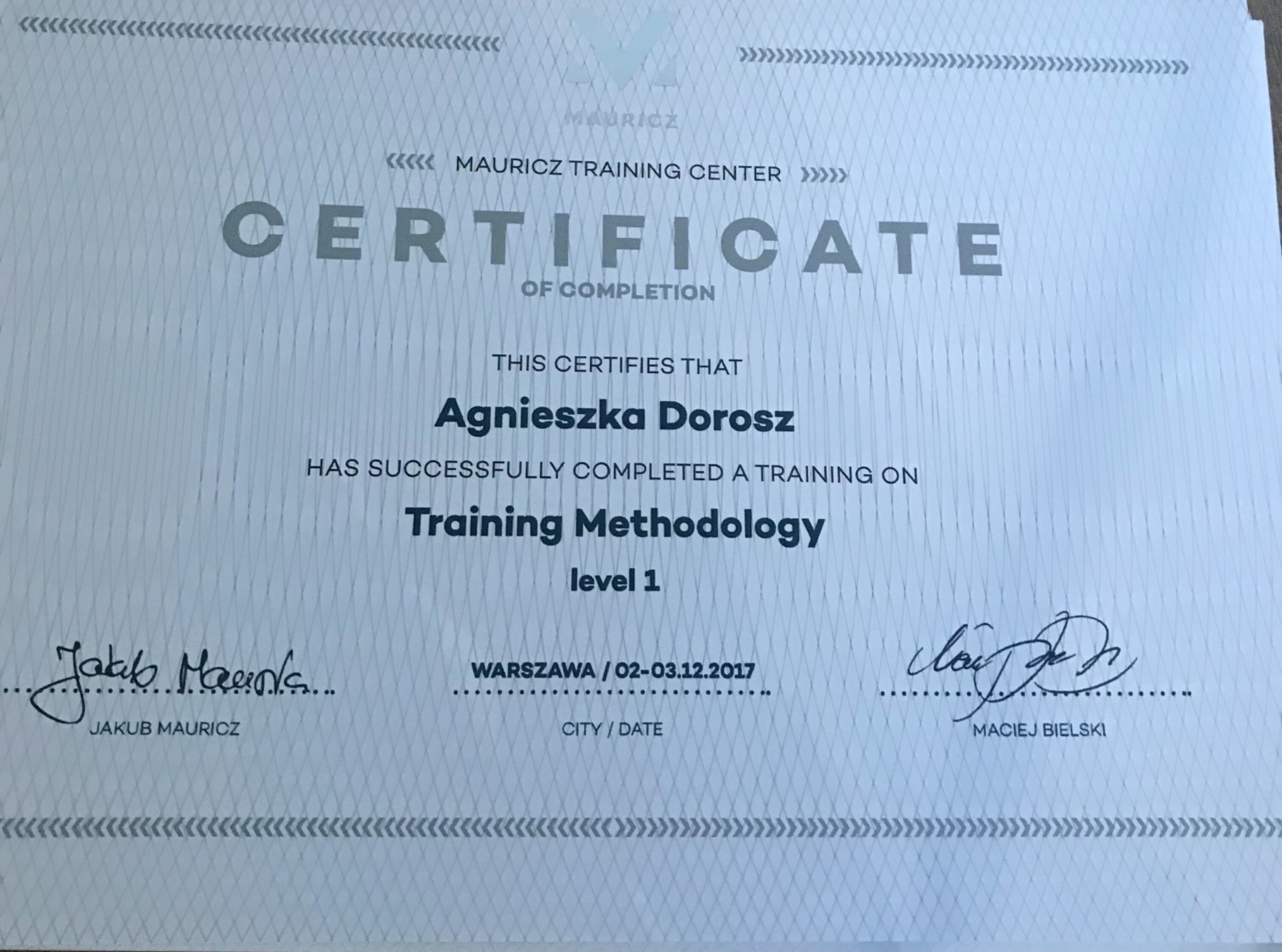 Certyfikat ukończenia szkolenia z metodologii treningu, poziom 1, wydany przez Mauricz Training Center dla Agnieszki Dorosz, podpisany przez Jakuba Mauricza i Macieja Bielskiego.