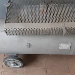 Szary zbiornik ciśnieniowy na kółkach z ażurową osłoną, prawdopodobnie po piaskowaniu, z widocznymi śladami niedokładnego czyszczenia.