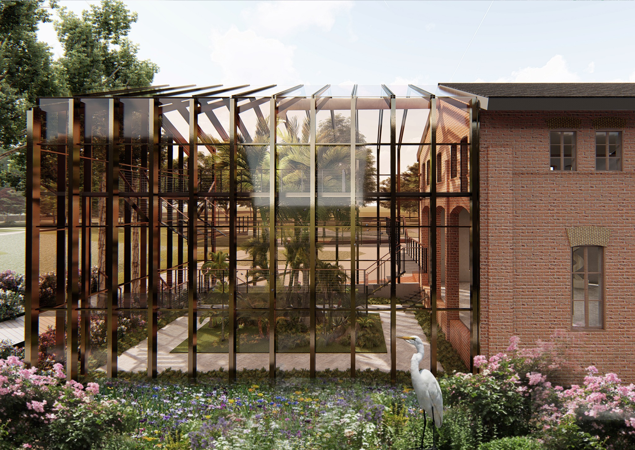 Szklana oranżeria z metalową konstrukcją przylegająca do ceglanego budynku, otoczona kwitnącymi rabatami i białym czaplem.