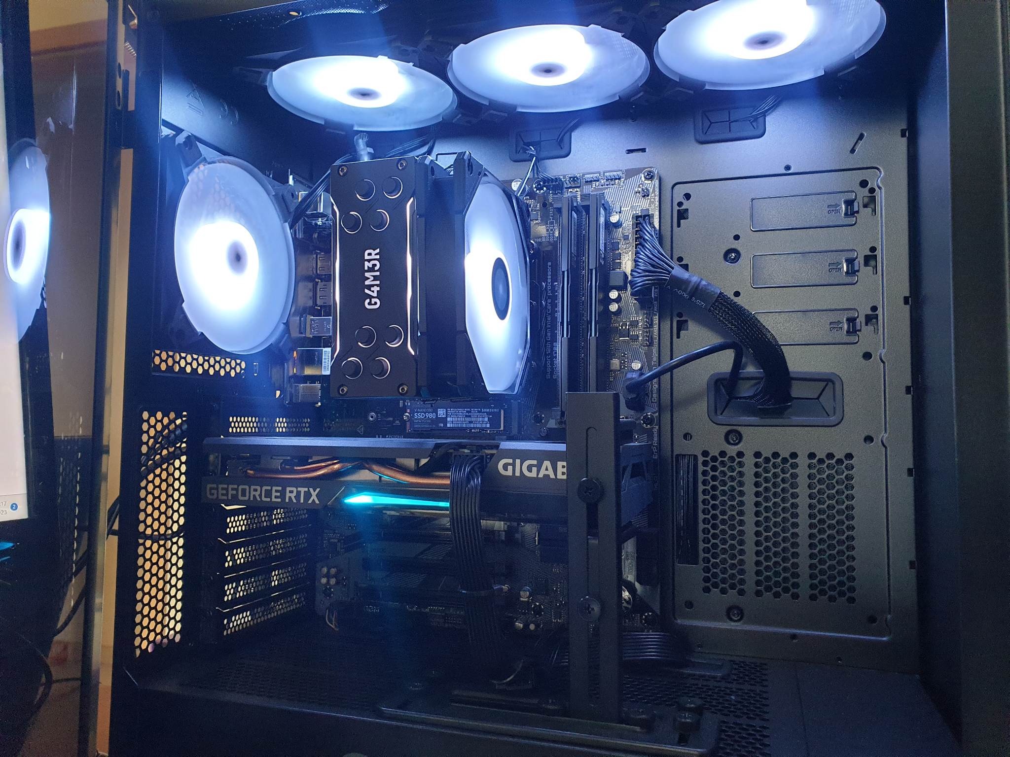 Wnętrze komputera stacjonarnego z podświetlanymi wentylatorami, kartą graficzną GeForce RTX i płytą główną GIGABYTE, widoczne komponenty chłodzenia procesora i pamięci RAM.