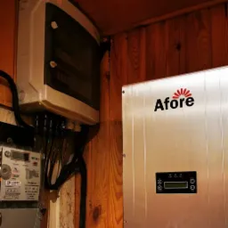 Szczegółowe ujęcie skrzynki elektrycznej, licznika i falownika Afore zamontowanych na drewnianej ścianie, z widocznymi kablami i przewodami.