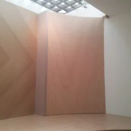 Narożnik z jasnego drewna z dekoracyjnym wzorem na ścianie i zakrzywionym elementem, oświetlony przez kratownicowy sufit.